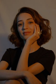 pexels photo 12239248 12239248 A sophisticated portrait of a woman with wavy hair wearing a t-shirt and ring indoors.