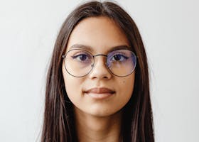 pexels photo 7588104 7588104 Headshot of a young woman wearing eyeglasses against a white background.